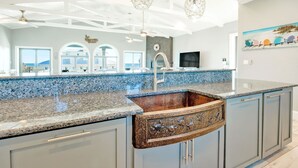 Una cocina moderna con encimera de granito, pileta integrada y un revestimiento original.