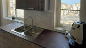 A modern kitchen with a built-in sink, dark cabinets, and a window with a city view. - Luxury Apartament's Celso (Palermo)