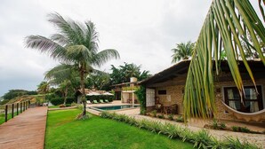 Una casa con piscina, rodeada de exuberante follaje y palmeras.