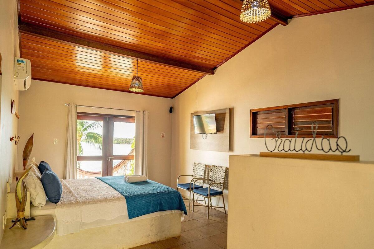A room with a bed, a desk, a chair, a TV, and a window with a view.