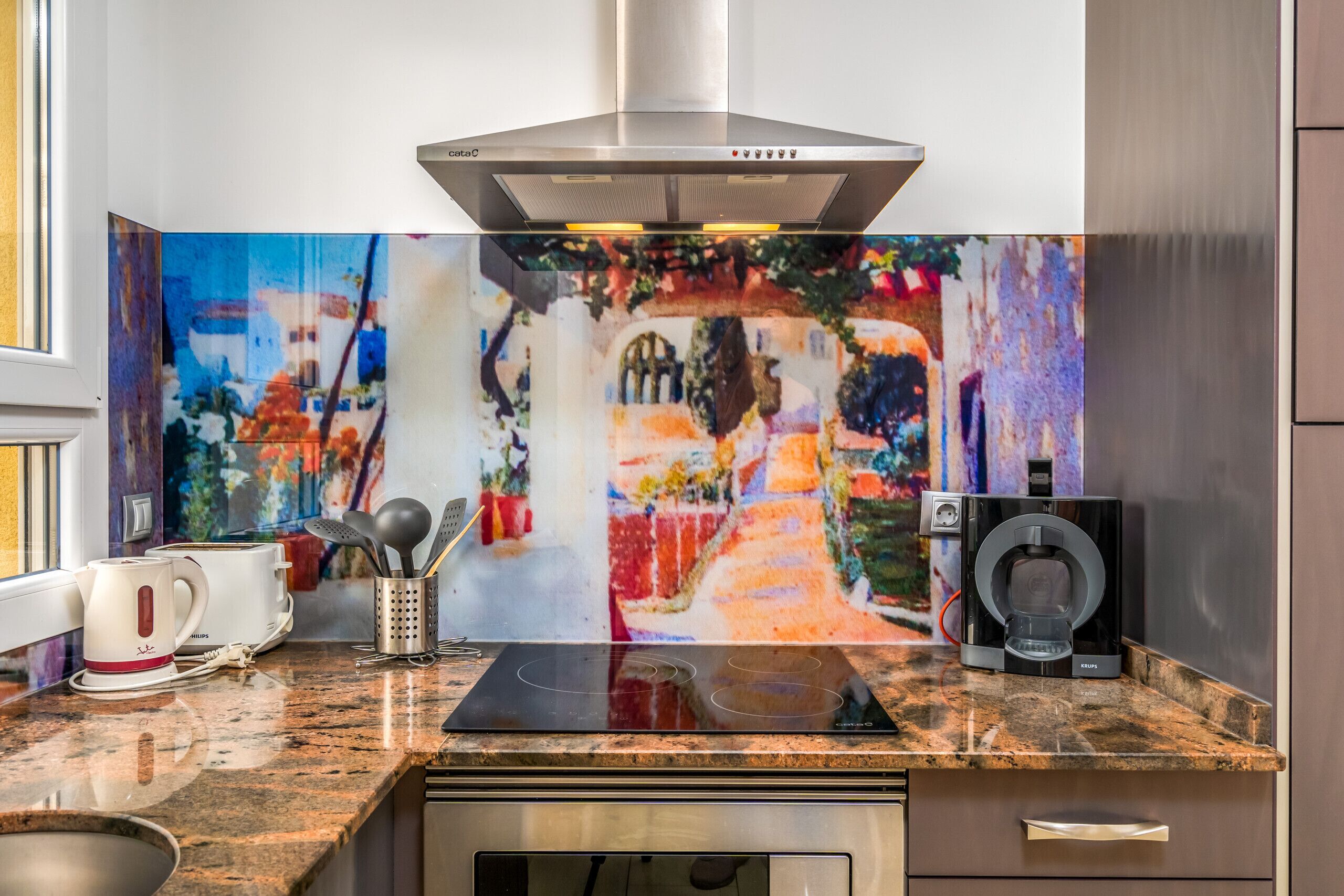 A modern kitchen with a stainless steel range hood, a coffee maker, a kettle, and a Krups coffee machine.