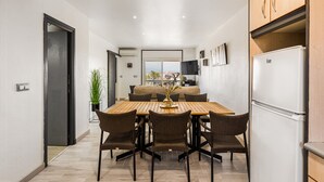Une cuisine moderne avec un coin repas, comprenant une table en bois, des chaises en osier et un réfrigérateur blanc.