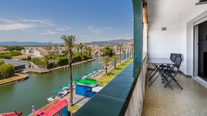 Un balcon offrant une vue sur une rivière, des bateaux et un paysage urbain lointain.