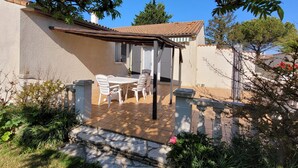 A patio area with a table and chairs, surrounded by stone walls and greenery. - VILLA 3 STARS 10 PEOPLE SWIMMING POOL SHOPS 1.2 km BEACHES  (Saint-Georges-de-Didonne)