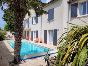 A poolside area with a clear pool, lounge chairs, and a palm tree. - VILLA 3 STARS 10 PEOPLE SWIMMING POOL SHOPS 1.2 km BEACHES  (Saint-Georges-de-Didonne)
