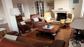 A living room with leather sofas, a wooden coffee table with a vase of flowers, and a fireplace. - VILLA 3 STARS 10 PEOPLE SWIMMING POOL SHOPS 1.2 km BEACHES  (Saint-Georges-de-Didonne)