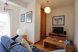 Ein Wohnzimmer mit einer Couch, einem Couchtisch, einem Fernseher und gerahmten Bildern an der Wand.
