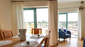 Un comedor con una mesa de madera, sillas y vistas a la ciudad a través de amplias ventanas.
