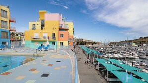 Un puerto deportivo con edificios coloridos, una piscina y barcos.