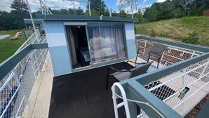Un petit espace extérieur clos, aménagé avec un banc et une table, et entouré d’une clôture en métal.