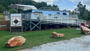 Un abri pour bateaux doté d’une terrasse couverte, d’une bouée de sauvetage et d’un petit pont menant au bateau.