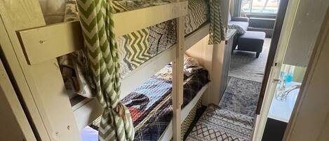 Habitación con literas, ropa de cama estampada y vistas a un espacio exterior.