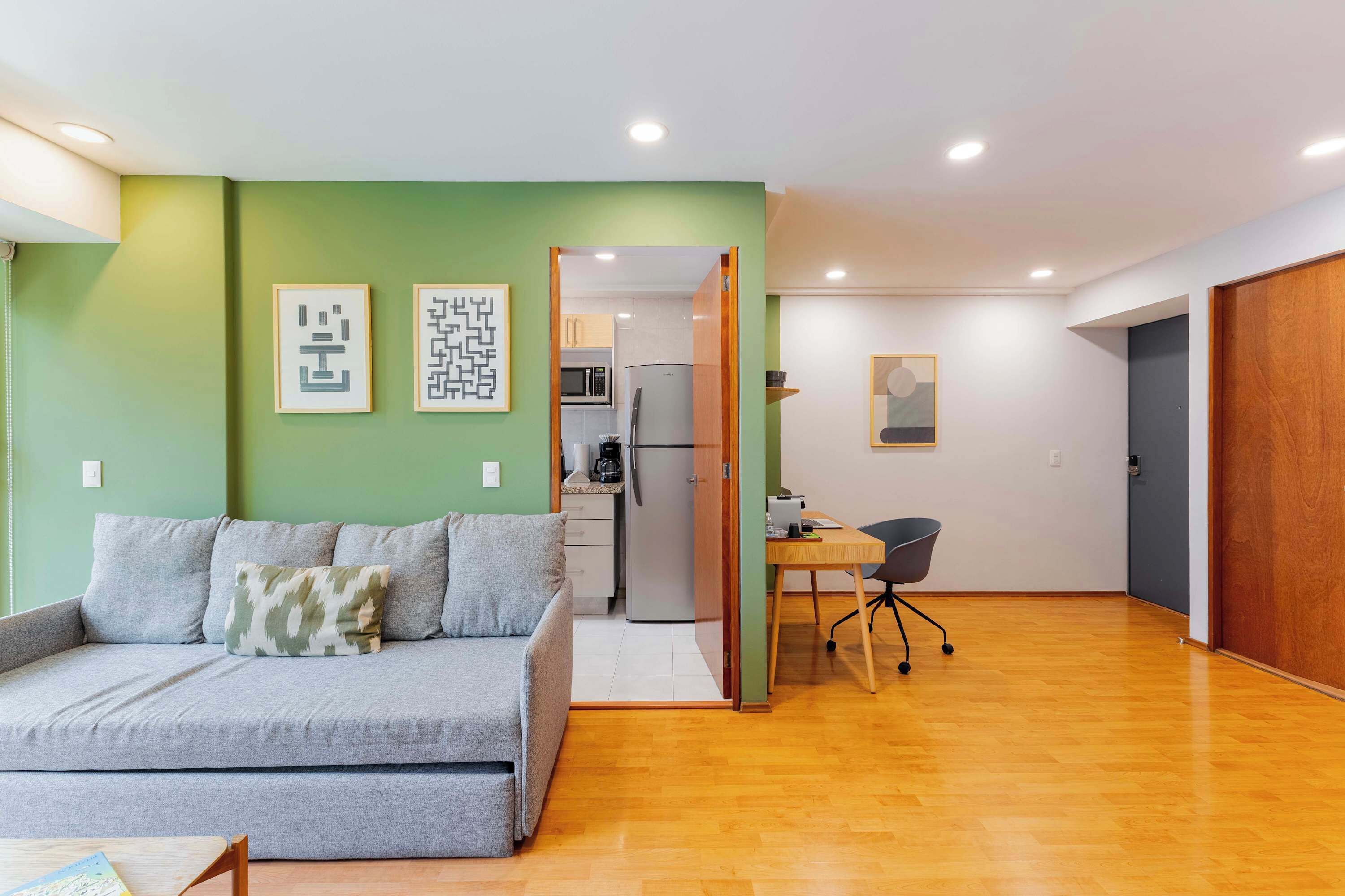 Ein modernes Wohnzimmer mit Sofa, Esstisch und einer Küche im Hintergrund.