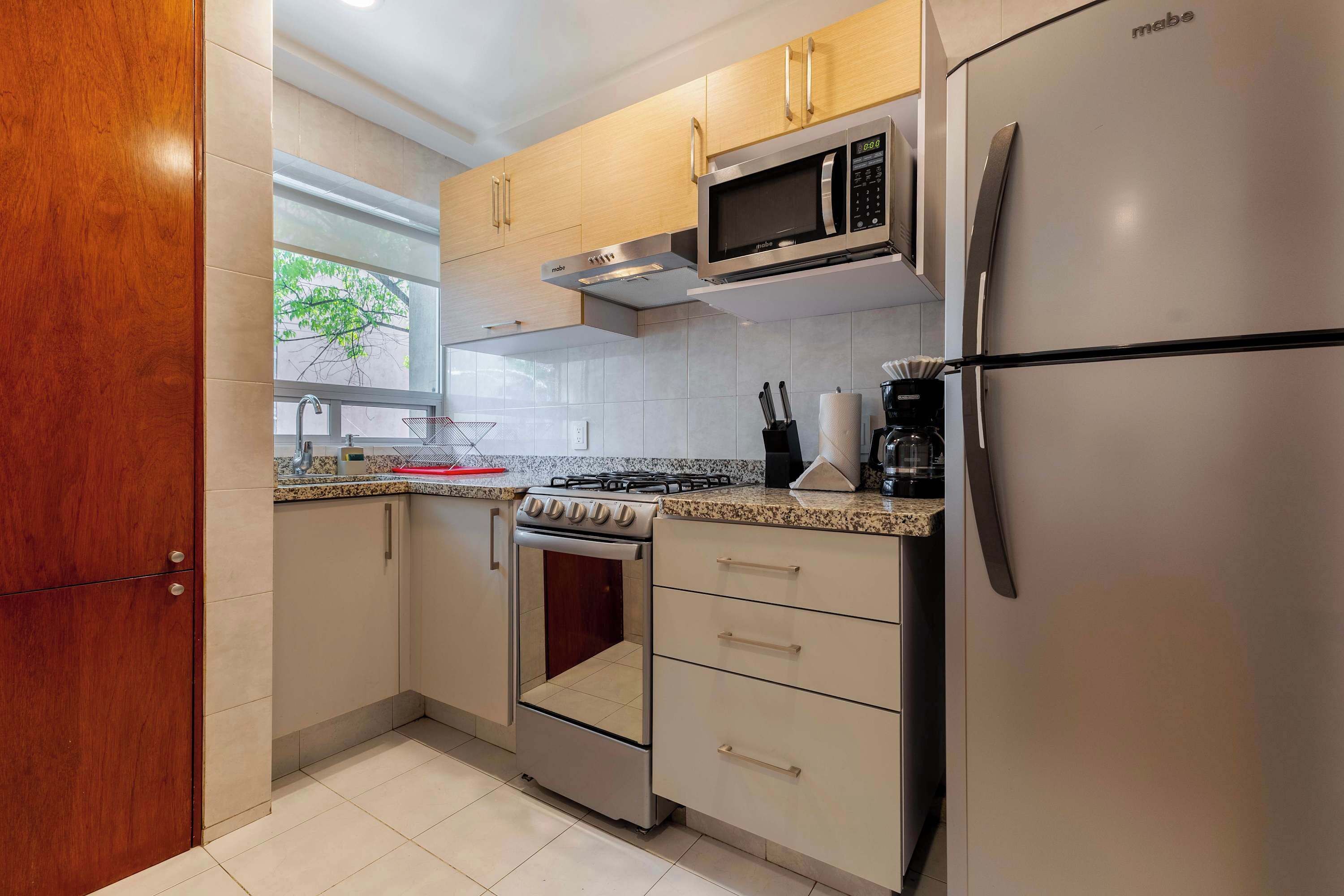 A kitchen with a stove, microwave, oven, and refrigerator.