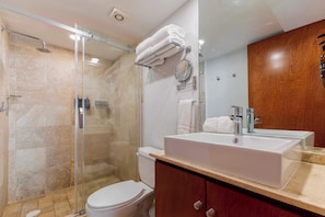 A modern bathroom with a glass shower enclosure, a white sink, and a wooden vanity.