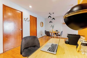 Une pièce moderne avec une porte en bois, un ordinateur portable sur une table, une bouteille d’eau et un sac noir.