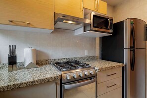 A modern kitchen with a gas stove, oven, microwave, and refrigerator.