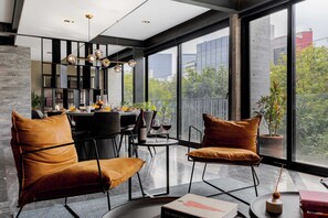 A modern living room with a dining area, large windows, and a view of the city.