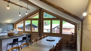Un'ampia cucina con un grande tavolo da pranzo, sedie in legno e vista sul paesaggio rurale attraverso ampie finestre.