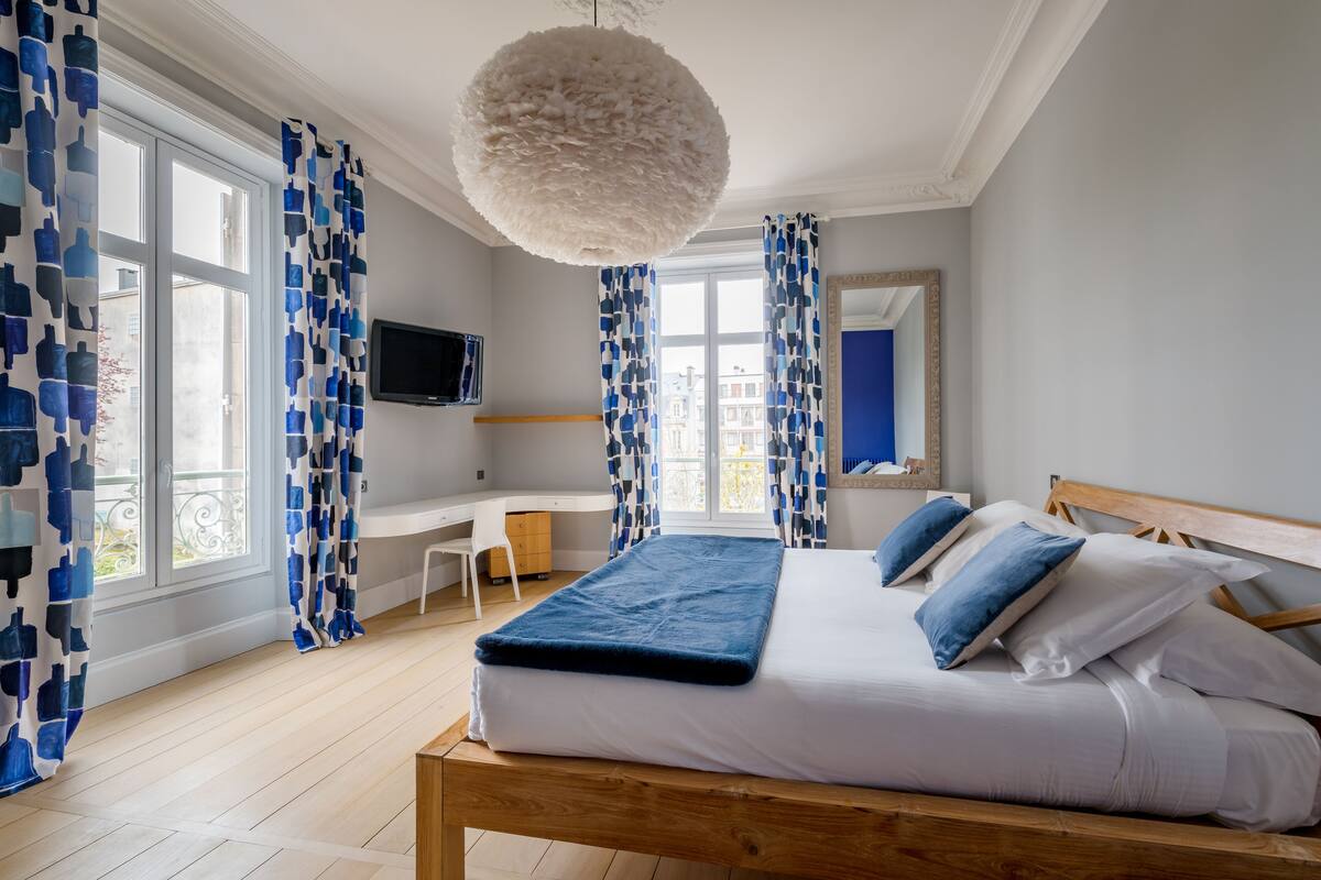 A bedroom with a large bed, a desk, and a television.