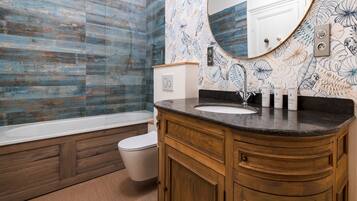 A bathroom with a wooden vanity, a white sink, and a shower with blue tiles.