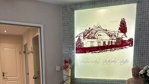 Ein Badezimmer mit gefliesten Wänden, einem Waschbecken, einer Schüssel, einer Statue und einem gerahmten Bild.