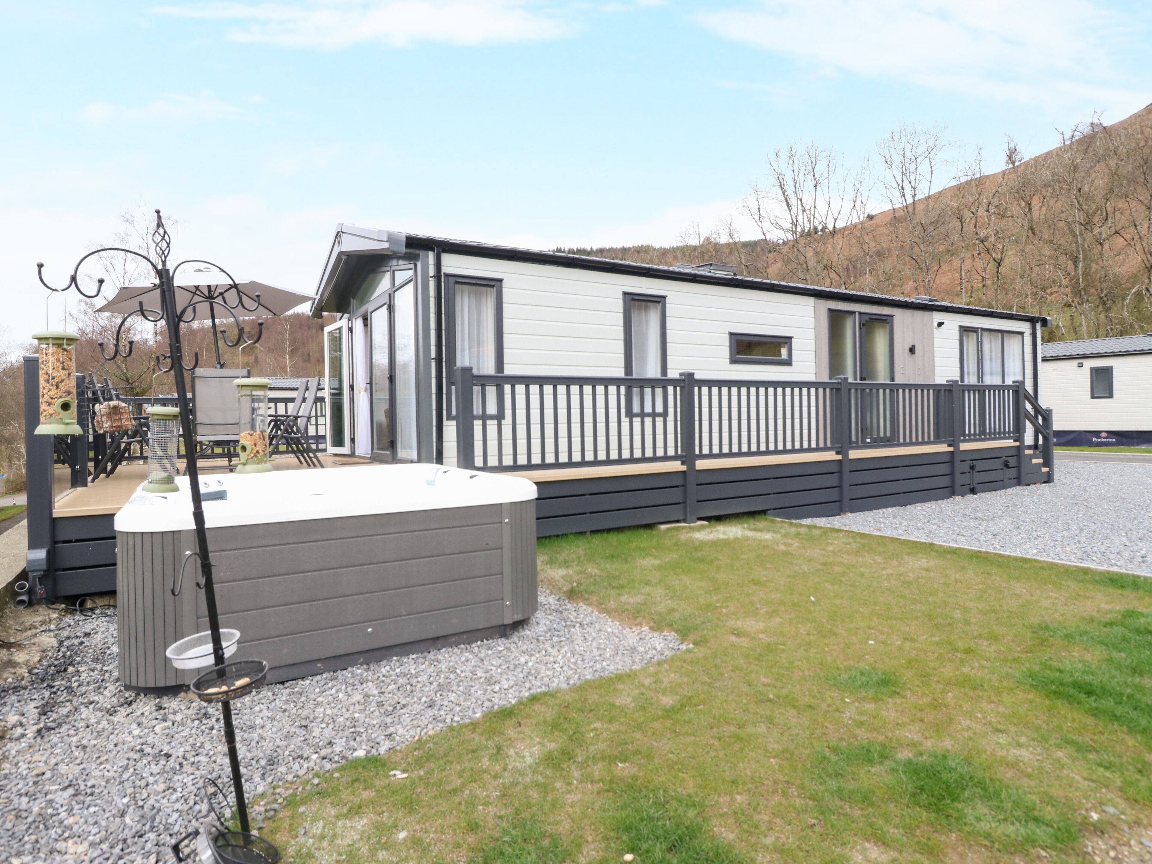 A mobile home with a deck, a hot tub, and a grill area.