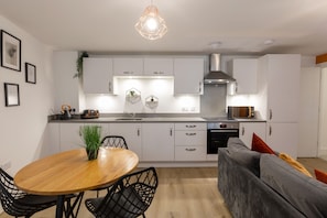 A modern kitchen with white cabinets, a stainless steel range hood, and a built-in oven. - The Courtyard (Southampton)