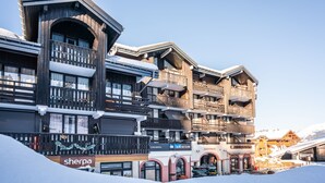 A multi-story hotel with balconies, a ski rental sign, and a Sherpa store. - Vacancéole - Grand Morillon (Morillon)