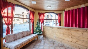 A wooden interior with a bench, red curtains, and a Christmas tree. - Vacancéole - Grand Morillon (Morillon)