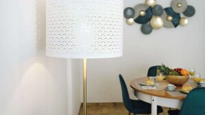 Un coin repas avec une table dressée pour deux personnes, une lampe et un élément décoratif mural.