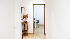 Un couloir avec une chaise en bois, une petite table et un miroir accroché au mur.