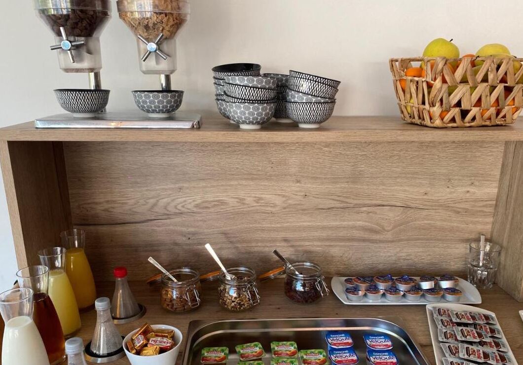 En köksbänk med olika livsmedel och förvaringskärl, inklusive skålar, burkar och förpackade snacks.