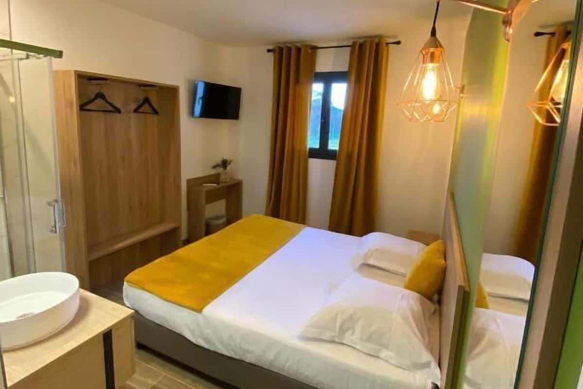 Ein Hotelzimmer mit Bett, Nachttisch, Spiegel, Kleiderschrank und Fernseher.