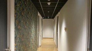 Un pasillo con piso de madera, paredes blancas y un papel tapiz con motivos florales en una pared.