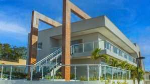 A modern building with a flat roof, large windows, and a central staircase. - Jardins da Lagoa - Casas Completas (Caldas Novas)