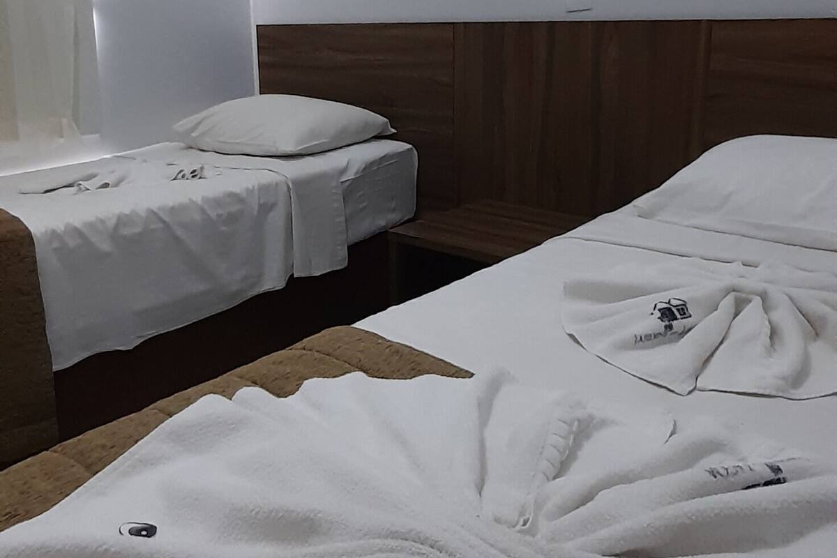 Ein Hotelzimmer mit zwei Betten, einem Holz-Kopfteil, einem Bild an der Wand und einem großen weißen Handtuch auf dem Boden.