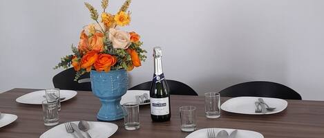 A dining table set with plates, cutlery, glasses, and a blue vase with flowers.