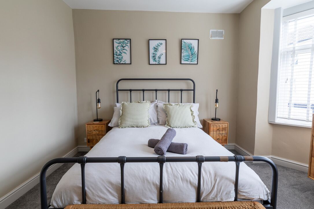 Una camera da letto con un letto, due comodini, una finestra e opere d'arte appese al muro.