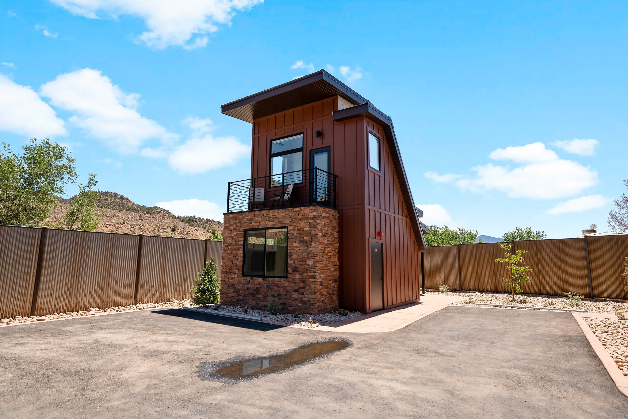 A modern two-story building with a balcony, a stone base, and a wooden upper section.