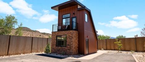 A modern two-story building with a balcony, a stone base, and a wooden upper section.