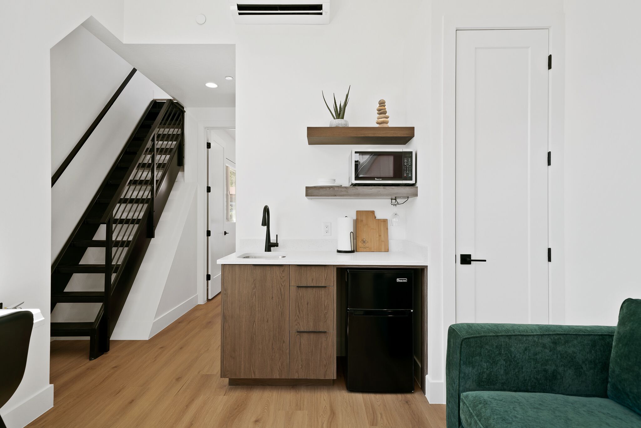 Une cuisine moderne dotée d’un four à micro-ondes encastré, de meubles en bois et d’un lave-vaisselle noir.