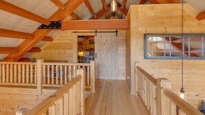 Un interior de madera con una escalera de madera, una lámpara colgante y un ventanal.