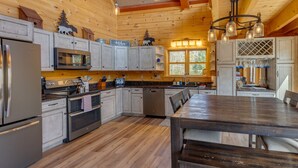 Cocina de cabaña de madera con mesa de comedor, electrodomésticos integrados y una araña.