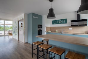 A modern kitchen with a central island, bar stools, and a pendant light. -  Shana Hotel & Residence (Chanaz)