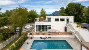 A modern building with a swimming pool, outdoor seating, and a view of the surrounding landscape. -  Shana Hotel & Residence (Chanaz)