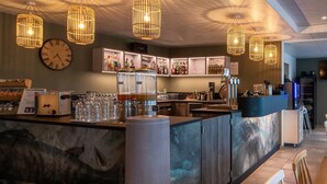 A bar area with a marble counter, hanging wicker light fixtures, and a clock on the wall. -  Shana Hotel & Residence (Chanaz)