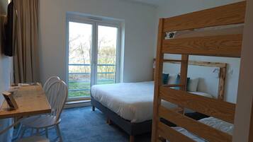 A room with a bunk bed, a desk with a chair, a window with curtains, and a view of the outdoors.