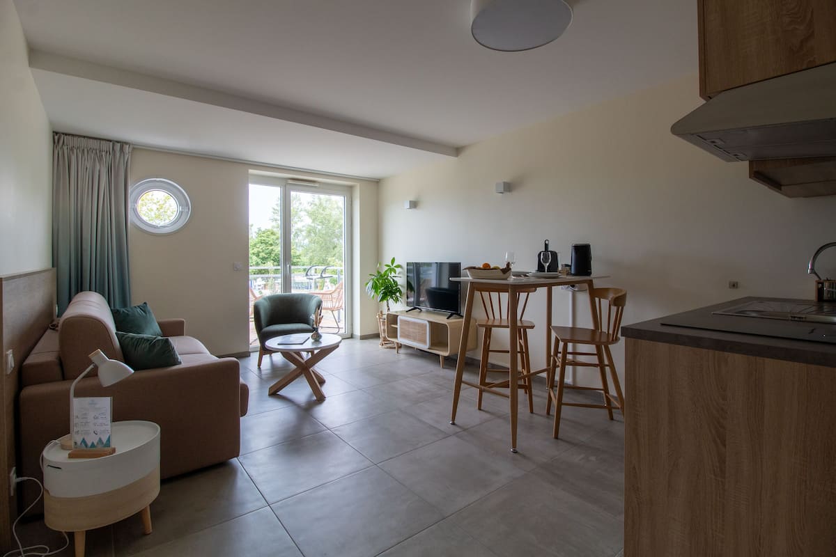 A modern living room with a sofa, TV, and dining area.