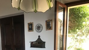 A dining area with a round table covered by a tablecloth with a nautical theme, a basket of apples, and a wall-mounted shelf with a decorative item. - Apartment (Sant'Ilario)